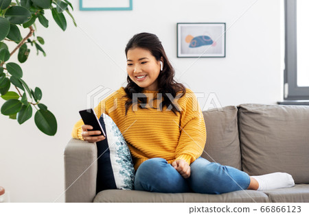 asian woman with earphones and smartphone at home asian woman with earphones and smartphone at home 66866123
