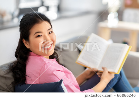smiling asian young woman reading book at home 66866246