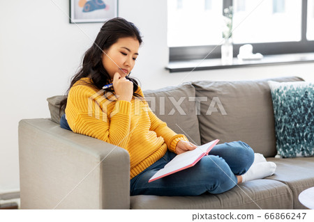 asian woman with diary sitting on sofa at home asian woman with diary sitting on sofa at home 66866247