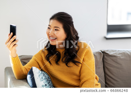 asian woman taking selfie with smartphone at home asian woman taking selfie with smartphone at home 66866248