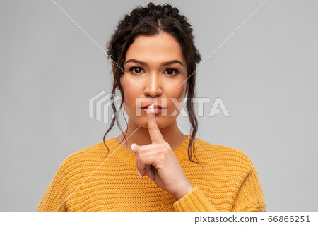 young woman with pierced nose making hush gesture 66866251
