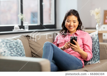 happy asian young woman with smartphone at home 66866384