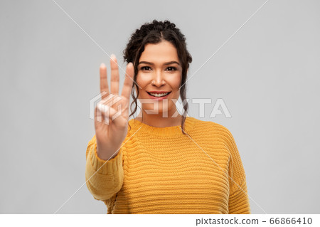 happy woman in pullover showing three fingers happy woman in pullover showing three fingers 66866410