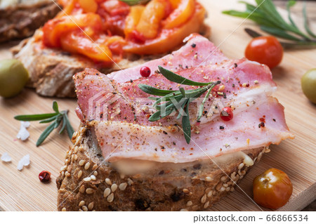 Wholegrain bread sandwiches with cream cheese, bacon and olives canned peppers with tomato on wooden background. Wholegrain bread sandwiches with cream cheese, bacon and olives canned peppers with tomato on wooden background. 66866534