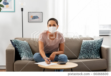 woman in mask with papers and calculator at home woman in mask with papers and calculator at home 66866600