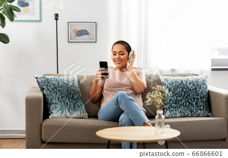 woman with smartphone listening to music at home woman with smartphone listening to music at home 66866601