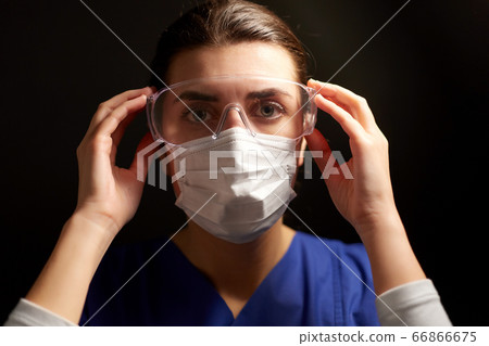 female doctor or nurse in goggles and face mask 66866675