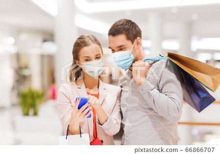 couple in masks with smartphone in shopping mall couple in masks with smartphone in shopping mall 66866707