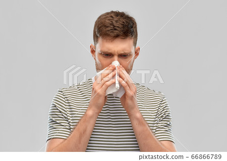 young man with paper tissue blowing his nose 66866789