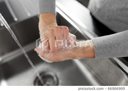 woman washing hands with soap in kitchen woman washing hands with soap in kitchen 66866900