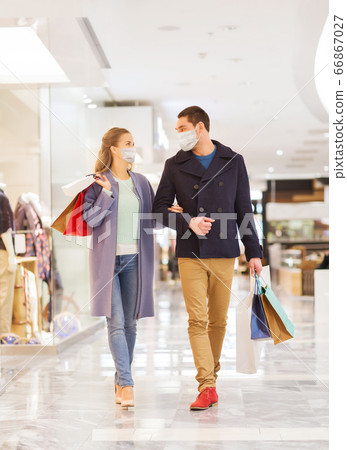 couple in medical masks with shopping bags in mall 66867027