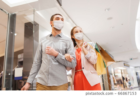 couple in medical masks with shopping bags in mall 66867153