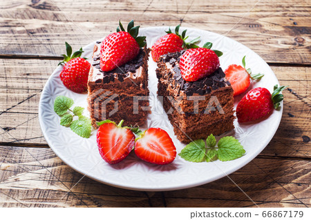Chocolate truffle cake with strawberries and mint. Wooden table. Chocolate truffle cake with strawberries and mint. Wooden table. 66867179