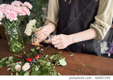 Floral shop concept . Florist woman creates flower arrangement in a wicker basket. Beautiful bouquet of mixed flowers. Handsome fresh bunch. Flowers delivery. Floral shop concept . Florist woman creates flower arrangement in a wicker basket. Beautiful bouquet of mixed flowers. Handsome fresh bunch. Flowers delivery. 66867260