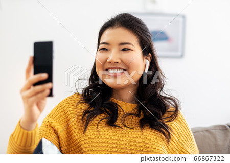 asian woman with earphones and smartphone at home asian woman with earphones and smartphone at home 66867322