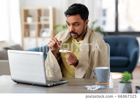 sick man thermometer having video call on laptop sick man thermometer having video call on laptop 66867325