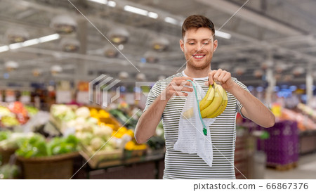 smiling man putting bananas into reusable net bag smiling man putting bananas into reusable net bag 66867376