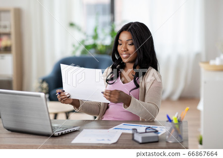 happy woman with laptop and papers at home office 66867664