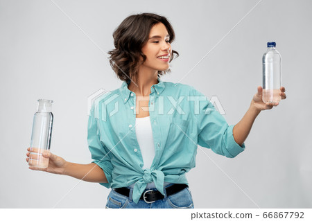 smiling young woman comparing bottles of water smiling young woman comparing bottles of water 66867792