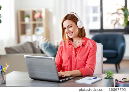 woman in headphones with laptop working at home woman in headphones with laptop working at home 66867793