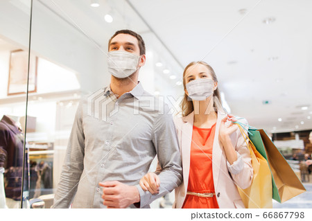 couple in medical masks with shopping bags in mall couple in medical masks with shopping bags in mall 66867798