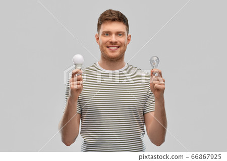smiling young man comparing different light bulbs smiling young man comparing different light bulbs 66867925