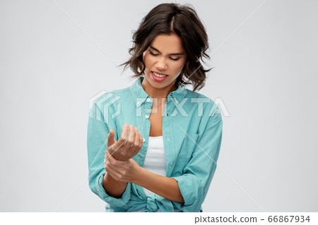 young woman in shirt suffering from pain in hand young woman in shirt suffering from pain in hand 66867934