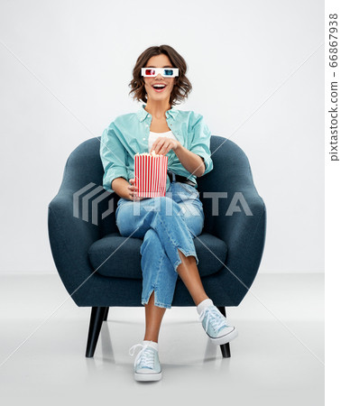 woman in 3d movie glasses eating popcorn in chair woman in 3d movie glasses eating popcorn in chair 66867938