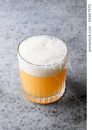 Pisco sour cocktail. Whiskey with lime, egg white, syrup in glass on grey. Vertical shot Pisco sour cocktail. Whiskey with lime, egg white, syrup in glass on grey. Vertical shot 66867970