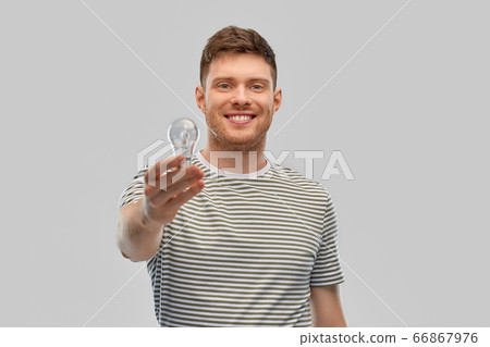 happy smiling young man holding light bulb happy smiling young man holding light bulb 66867976