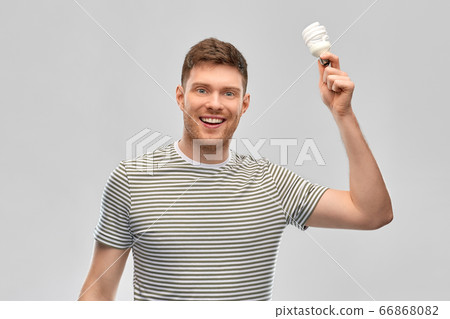 smiling young man holding lighting bulb 66868082