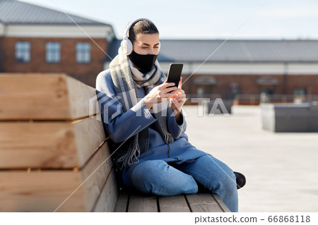 woman in face mask with smartphone in city woman in face mask with smartphone in city 66868118