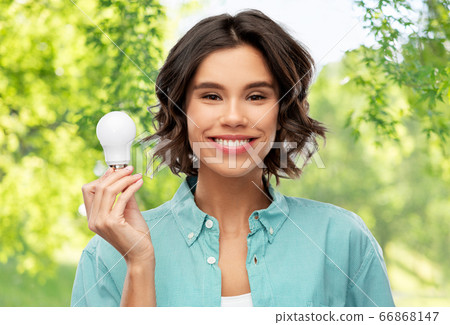 smiling woman holding energy saving lighting bulb 66868147