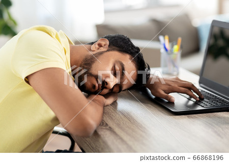 indian man sleeping on table with laptop at home indian man sleeping on table with laptop at home 66868196
