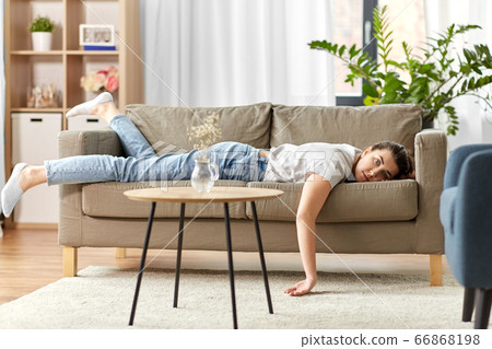 bored or lazy young woman lying on sofa at home bored or lazy young woman lying on sofa at home 66868198