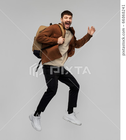 smiling young man with backpack jumping in air 66868241