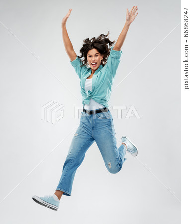 happy young woman jumping over grey background happy young woman jumping over grey background 66868242