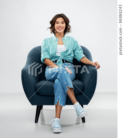 happy smiling young woman sitting in armchair happy smiling young woman sitting in armchair 66868243