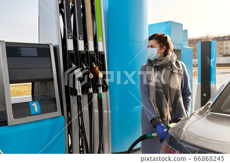 woman in mask filling car at gas station woman in mask filling car at gas station 66868245
