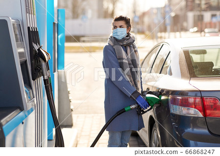 woman in mask filling her car at gas station woman in mask filling her car at gas station 66868247