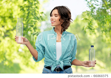 smiling young woman comparing bottles of water 66868375