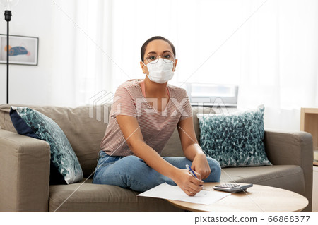 woman in mask with papers and calculator at home woman in mask with papers and calculator at home 66868377