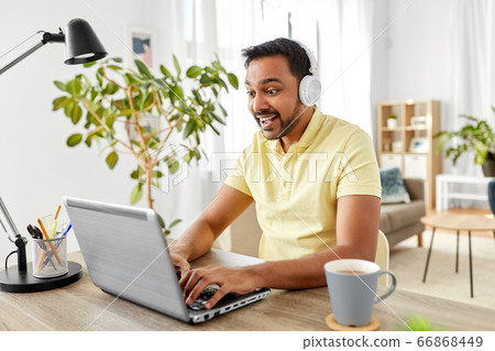 man in headphones with laptop working at home man in headphones with laptop working at home 66868449