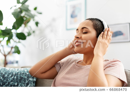woman in headphones listening to music at home woman in headphones listening to music at home 66868470