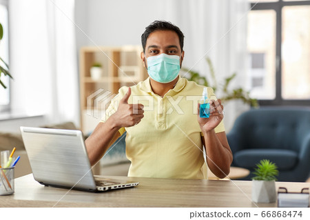 man in mask with hand sanitizer at home office man in mask with hand sanitizer at home office 66868474