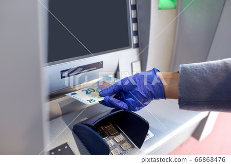 hand in medical glove with money at atm machine hand in medical glove with money at atm machine 66868476