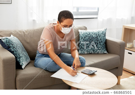 woman in mask with papers and calculator at home woman in mask with papers and calculator at home 66868501