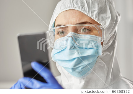 doctor in protective wear with smartphone 66868532