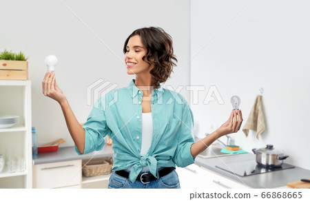 smiling woman comparing different light bulbs smiling woman comparing different light bulbs 66868665