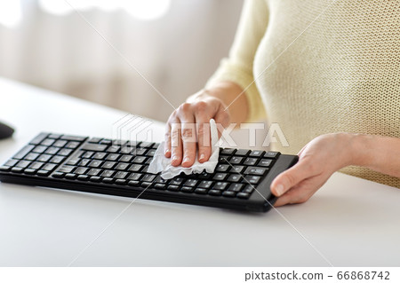 close up of woman cleaning keyboard with tissue 66868742